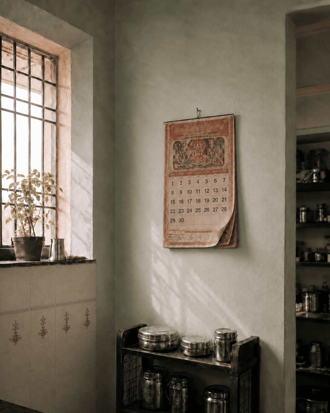 A panchang calendar hanging on a kitchen wall, morning light