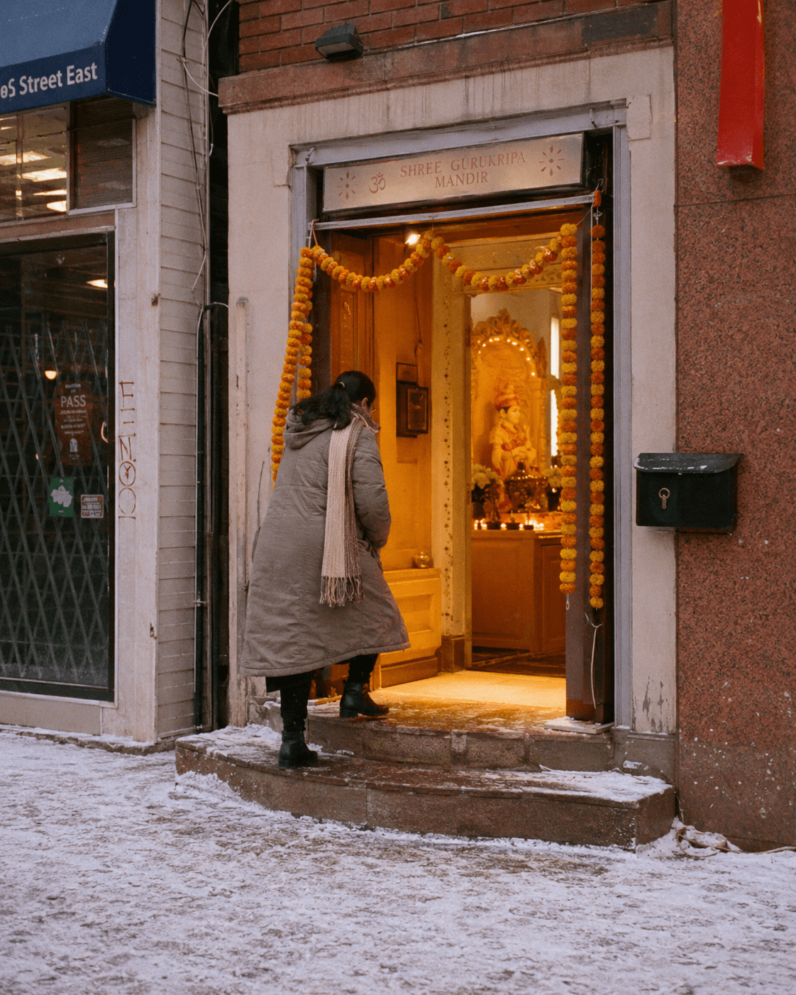 A woman entering a small storefront mandir on Gerrard Street on a snowy Saturday morning