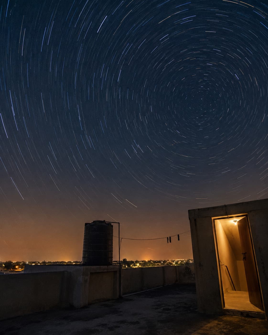 Star trails wheeling across the night sky above a rooftop terrace